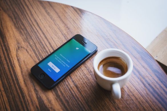 twitter on phone sitting on table with coffee cup