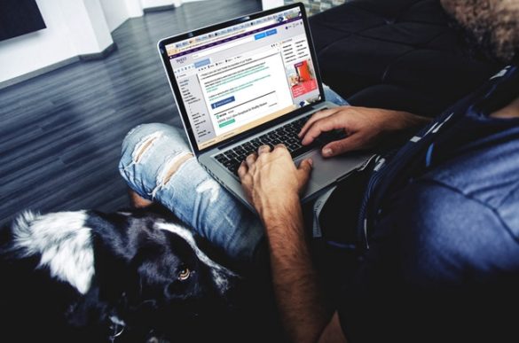man typing on laptop with dog
